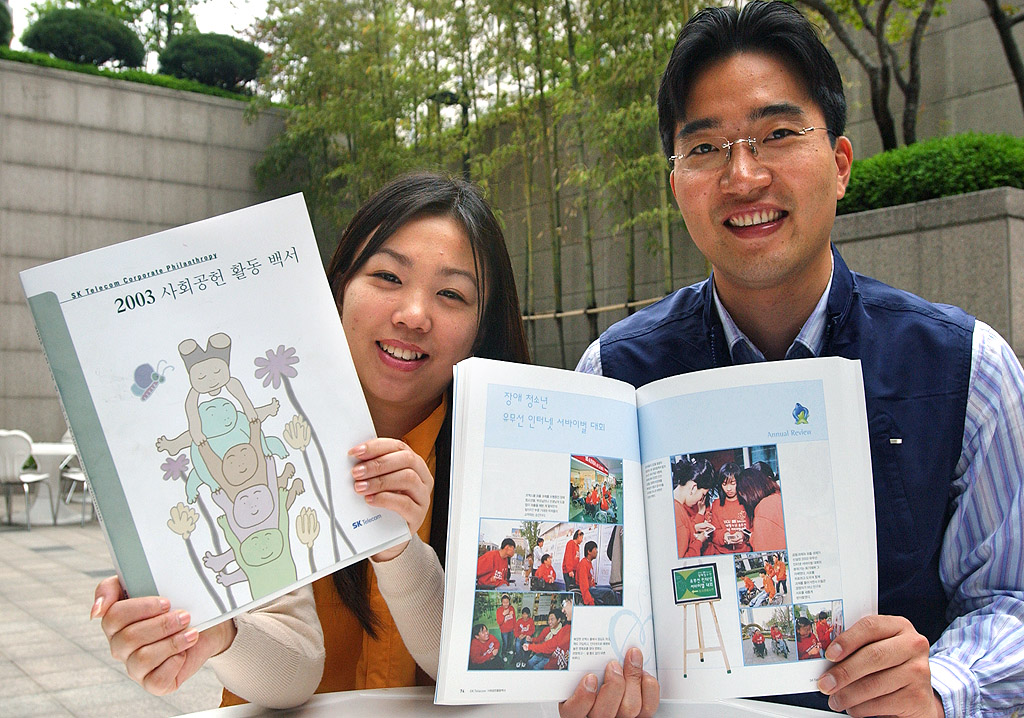 An SK Telecom employee is shown taking a look at the `2003 Social Contribution White Book`. (SK Telecom published the `2003 Social Contribution White Book` that outlines the many social contribution activities carried out under the slogans `Heart of Togetherness`, and `Happy Korea`).